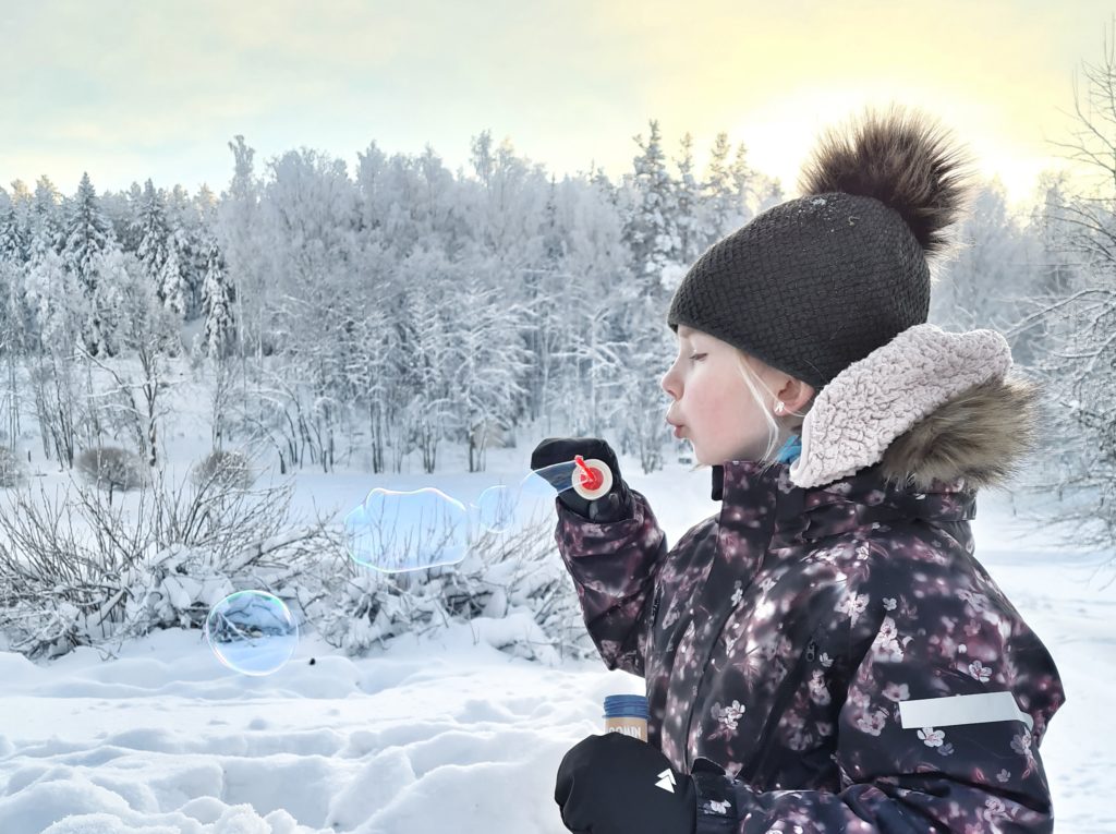 Ett barn blåser bubblor ute i kylan